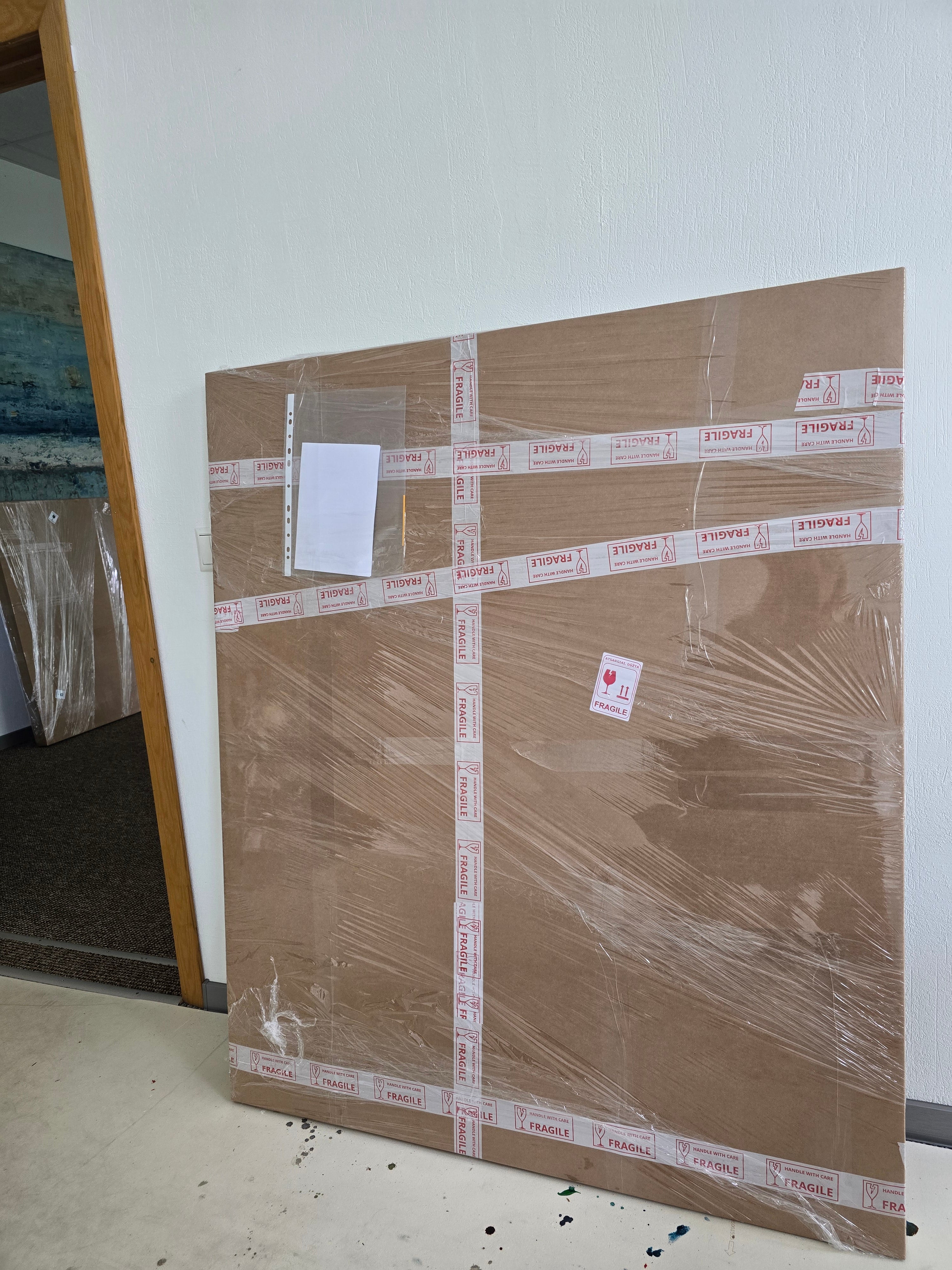 Ready to ship art in a large brown cardboard panel in Birute Studio.