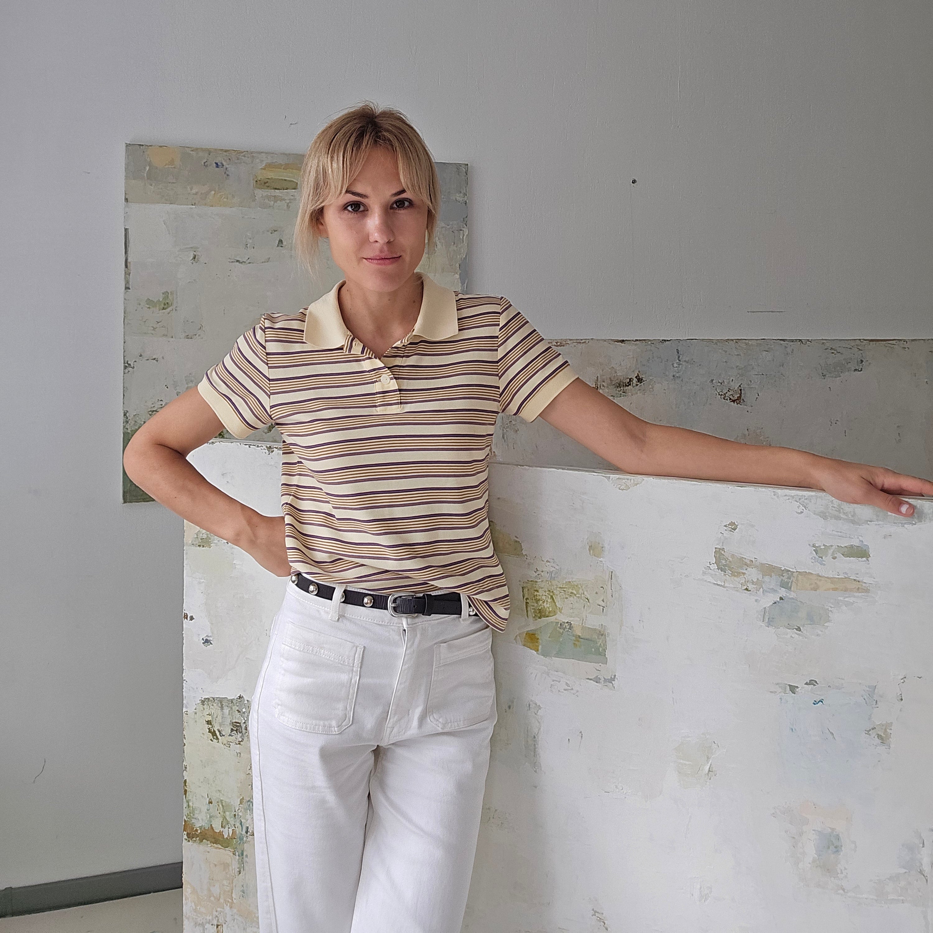 Birute in her studio in Vilnius standing next to her latest original painting in white, neutral tones.